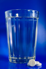 glass of clean water and a tablet on a light background.