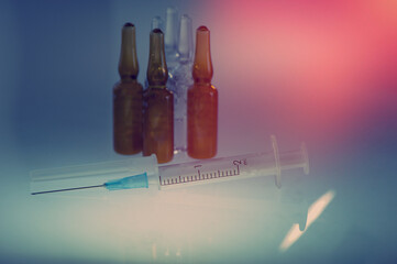 Disposable syringes and vaccine vials lie on the tabletop in the room.