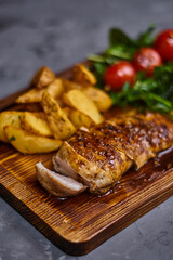 Chicken fillet in sweet and sour sauce with potatoes on a wooden board