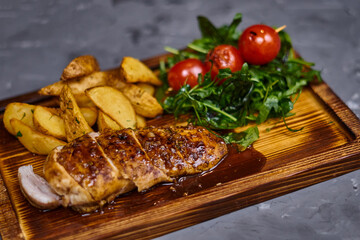 Chicken fillet in sweet and sour sauce with potatoes on a wooden board