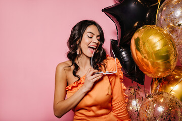 Appealing latin female model celebrating birthday. Indoor shot of laughing brunette woman with helium balloons.