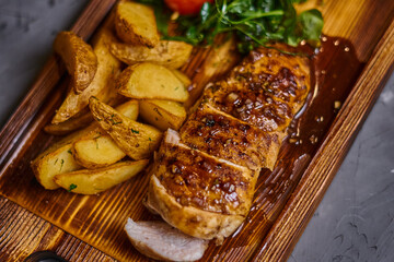 Chicken fillet in sweet and sour sauce with potatoes on a wooden board