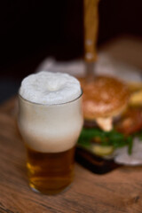 A glass of beer with foam and a burger