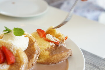 Person holding a fork of Fluffy pancake with Chocolate nuts sauce.