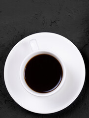A cup of coffee on a black stone background. White cup. Flat lay