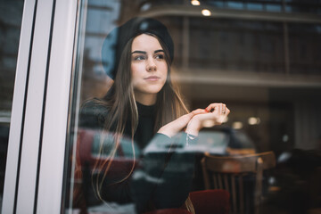 Dreamy woman sitting in cafe and looking away