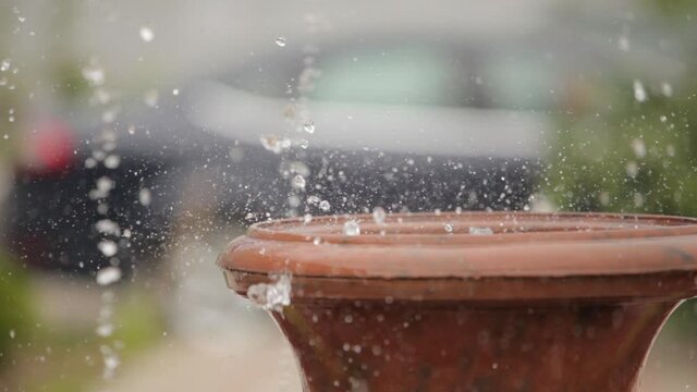 Close-up view of drops and splashes of water in a fountain. Water is pouring from a brown vessel