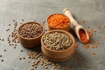Scoop and bowls with different legumes on gray background