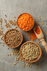 Scoop and bowls with different legumes on gray background