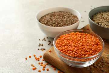 Board with bowls with legumes on white textured background