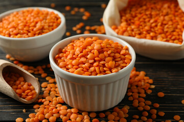 Bag, scoop and bowls with red legumes on wooden background