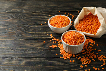 Bag and bowls with red legumes on wooden background