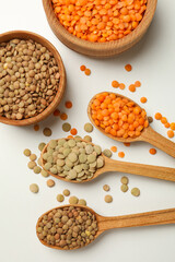 Spoons and bowls with different legumes on white background