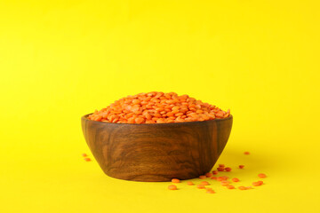 Bowl with red legumes on yellow background, space for text