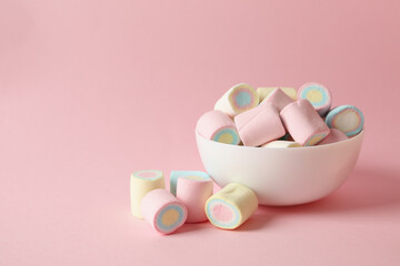 Bowl with marshmallow on pink background, space for text