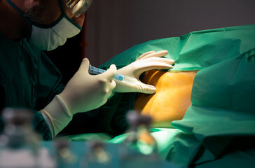 Anesthesiologist or doctor prepping area where her is going to do a Epidural nerve or spinal block for a patient who is about to have a give birth per vaginal or cesarean section. Anesthetic injection - obrazy, fototapety, plakaty