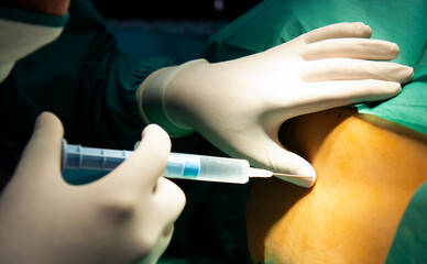 Anesthesiologist or doctor prepping area where her is going to do a Epidural nerve or spinal block for a patient who is about to have a give birth per vaginal or cesarean section. Anesthetic injection - obrazy, fototapety, plakaty