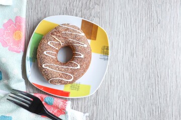 View from above of a donut on the plate with a napkin on the wooden table 