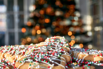 Christmas cookies with red and green in front of a blurred Christmas tree with lights. Image with selective focus and copy space.