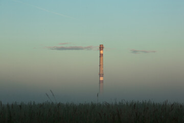 Obraz premium Factory chimney in the morning in fog.