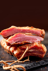 Dried pork ribs close-up on a dark table. Sliced jerky pork meat. Copy space for text.