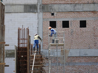 MALACCA, MALAYSIA -MARCH 12, 2020: Construction workers working at height at the construction site. They are supplied with harnesses and other safety equipment to prevent them from having an accident.