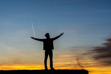 Young man celebrating life under beautiful evening sky