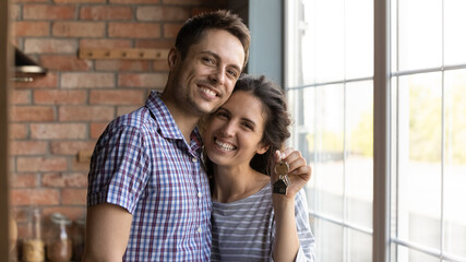 Happy houseowners. Portrait of excited millennial family couple posing indoors at rented house....