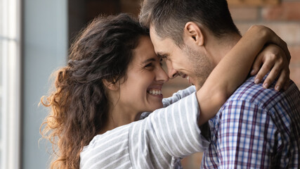 Love in your eyes. Loving millennial woman embracing neck of beloved man with warmth care. Happy wife girlfriend looking in husband boyfriend eyes smiling touching forehead share affectionate feeling