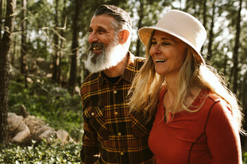 happy smiling senior couple walking through forest on sunny day 