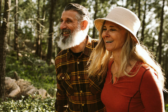 happy smiling senior couple walking through forest on sunny day  - Powered by Adobe