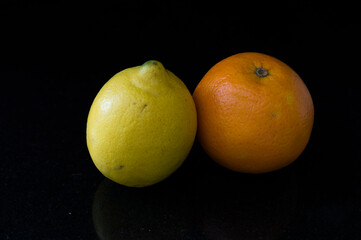 A lemon and an orange with black background
