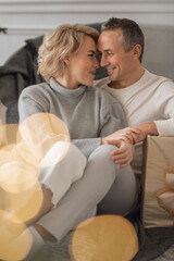 adult man and woman sit on the floor near the couch and hug