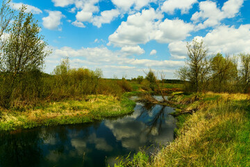 The river among green fields and clouds reflecting in the water in spring at times. fresh spring...