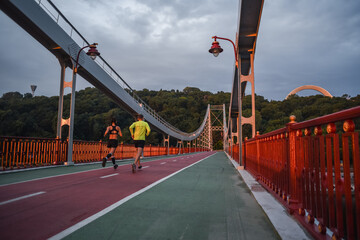 sporty couple running outdoors on the bridge during sunrise