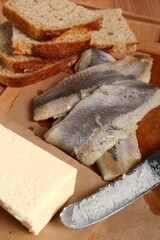 Making sandwiches with pickled herring and butter. Salted, soused skinless fillets of fish Clupea.