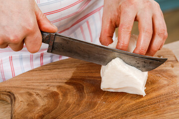 Cook cuts raw pork fat into small pieces on a wooden cutting Board.