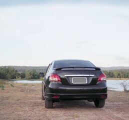 .A black car parked near the reservoir.To picnic