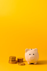 White piggy bank and coins on yellow color background. Saving, money accumulation, investment,...
