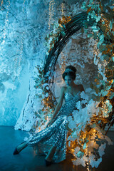 A woman in the form of a snow queen in a fairy-tale setting in mystical blue lighting ..