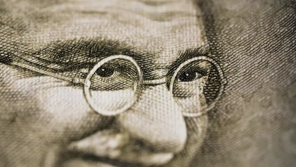 Dramatic close of eyes of Mahatma Gandhi on Rupee bill with flashing light. Extreme details of Indian currency. Angry symbol for nonviolent resistance and civil rights freedom movements. 4K.