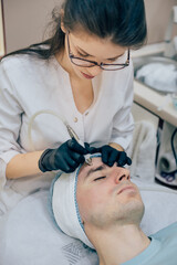 Men`s cosmetology. Young male receiving facial procedures at beauty clinic