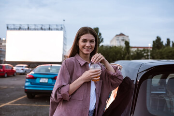 Young happy caucasian girl standing on auto cinema parking