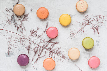 Colorful french macarons on white rustic background, top view