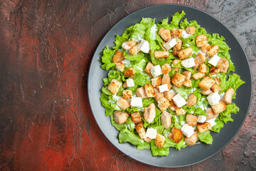 top view caesar salad on oval plate on dark red background food photo