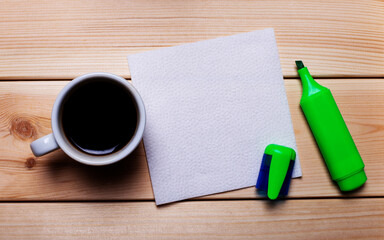 Green marker, coffee cup and white napkin on a wooden table. Background for text.