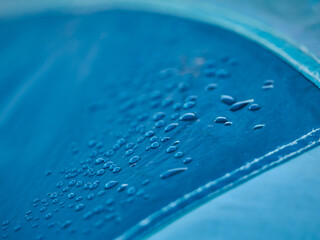 Water drops on waterproof membrane fabric. Detail view of texture of blue synthetic waterproof cloth. Morning dew on tent.