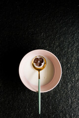 Luxurious green and golden spoon with cereals on a pink bowl full of milk isolated on a black background