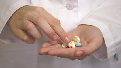 Pain reliever pills in the female hand of a medical professional in a white coat. Capsules with medicines, taking medication, healthcare, pharmacy and treatment concept, close up view