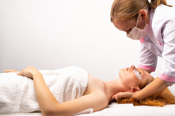 The beautician gives the girl a professional face, neck, body massage. Photo on white background